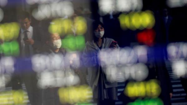 Pedestrians wearing facial masks are reflected on an electric board showing stock prices outside a brokerage at a business district in Tokyo, Japan January 30, 2020. REUTERS/Kim Kyung-Hoon