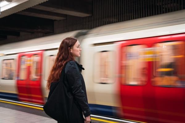 Young woman standing in front of subway at platform