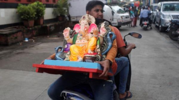 A devotee carries an idol of the Hindu God Ganesh, the deity of prosperity, on a scooter, on the eve of the Ganesh Chaturthi festival in Mumbai, India, September 9, 2021. REUTERS/Francis Mascarenhas/File Photo